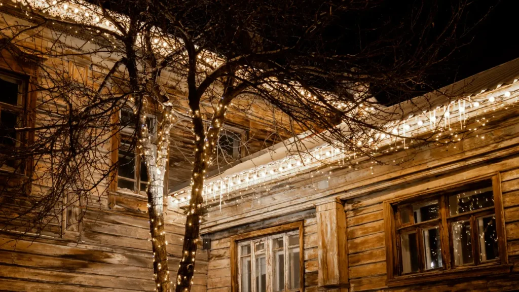 Christmas light installation on wooden house with illuminated trees and holiday decorations